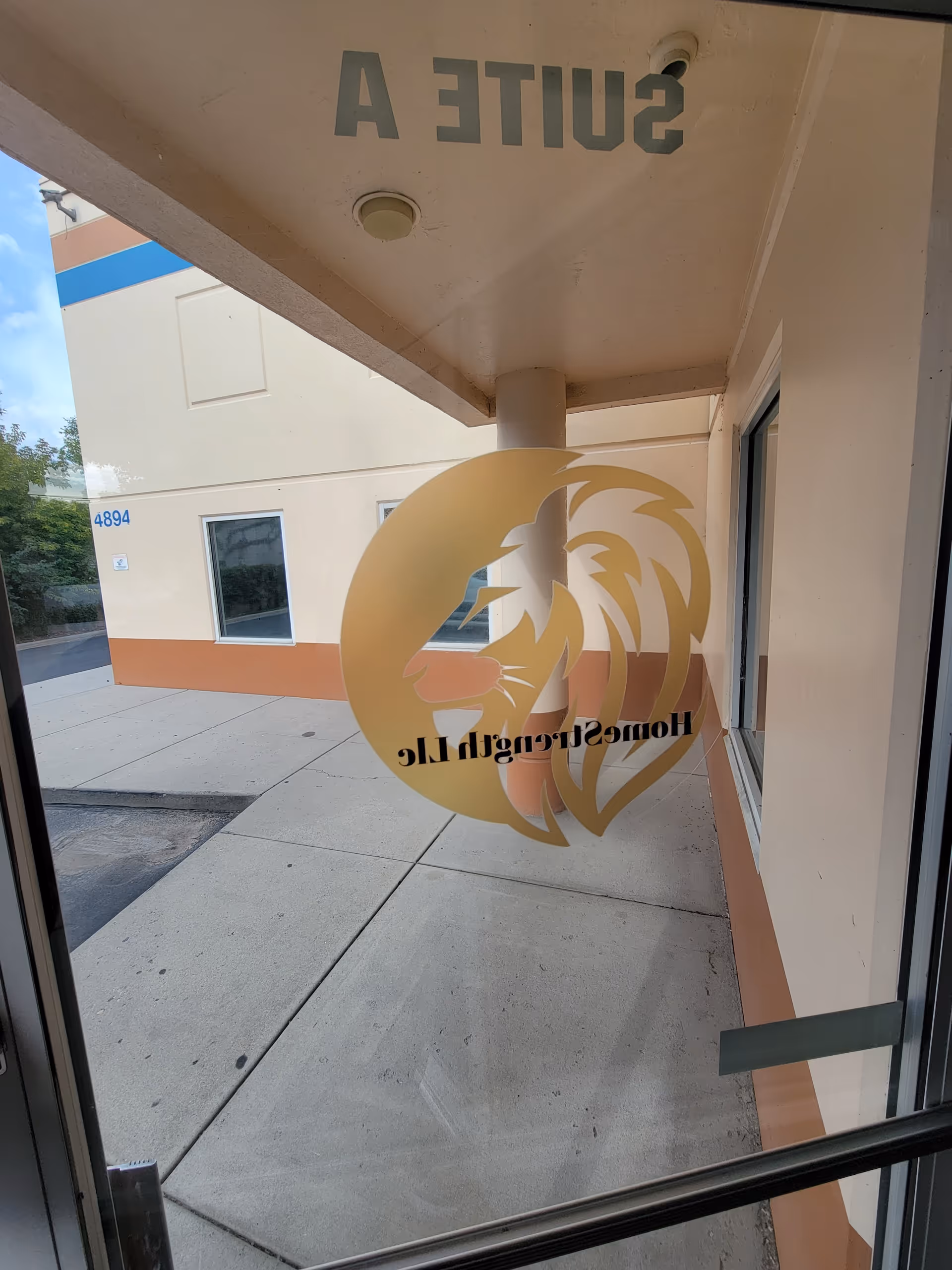 Glass entrance door for HomeStrength LLC with logo and sidewalk outside.