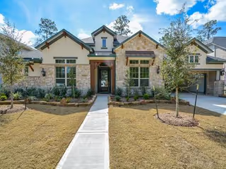 A modern stone-and-siding senior living facility front entrance with a paved walkway.