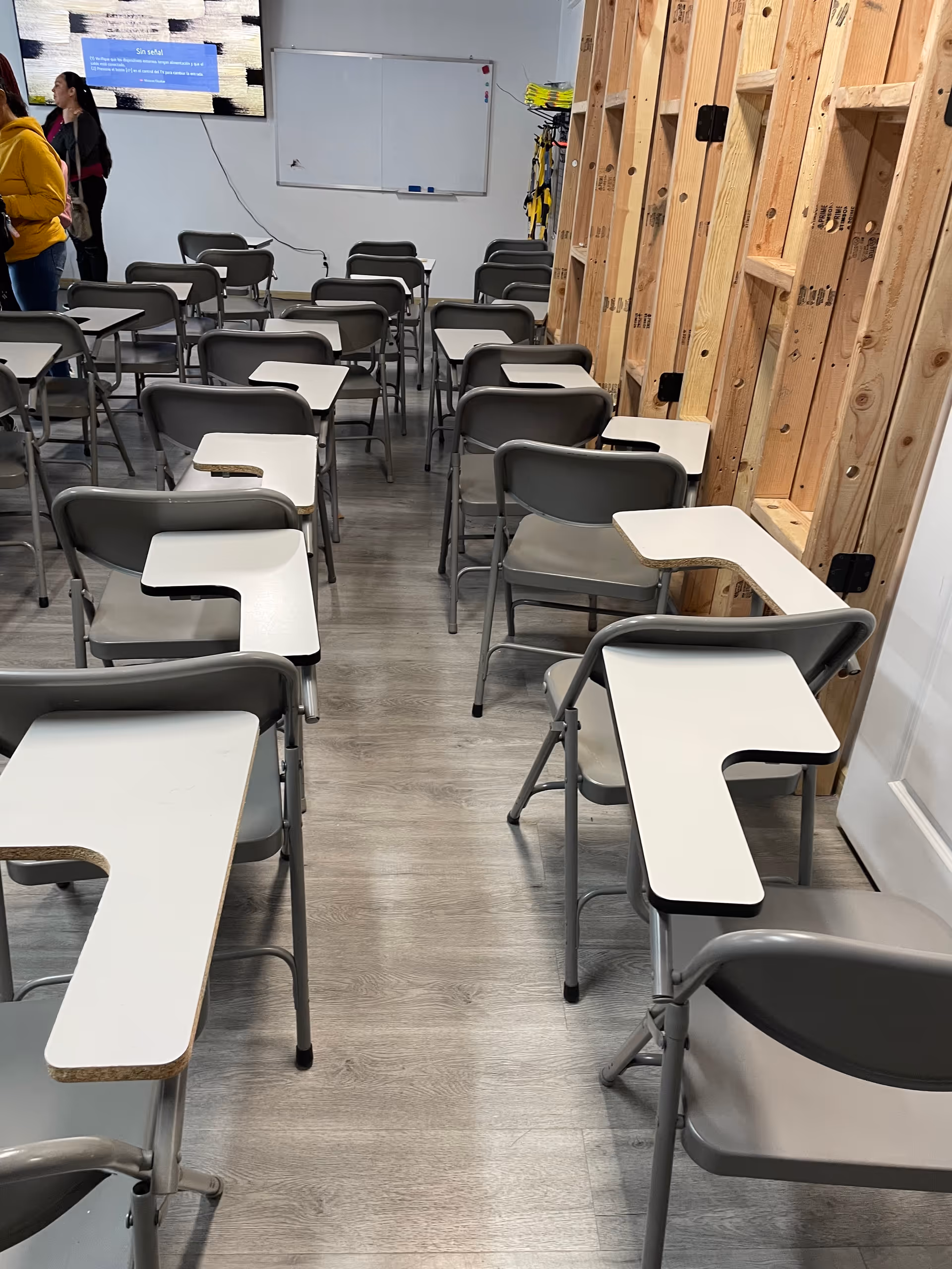 Training room with rows of desks attached to chairs and a whiteboard.