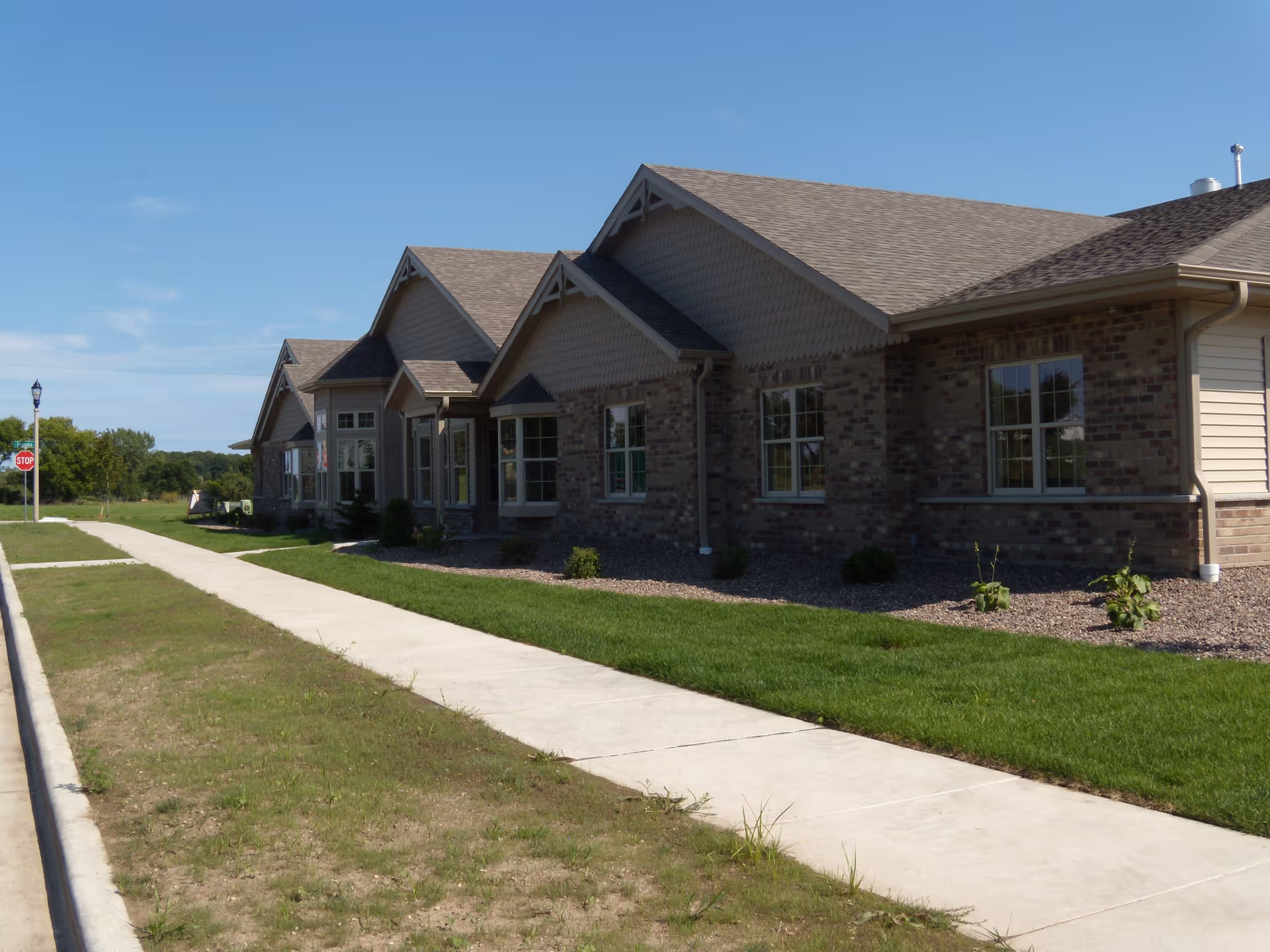 Exterior view of Ivy Manor of West Bend, a senior living facility, with sidewalk and landscaping.