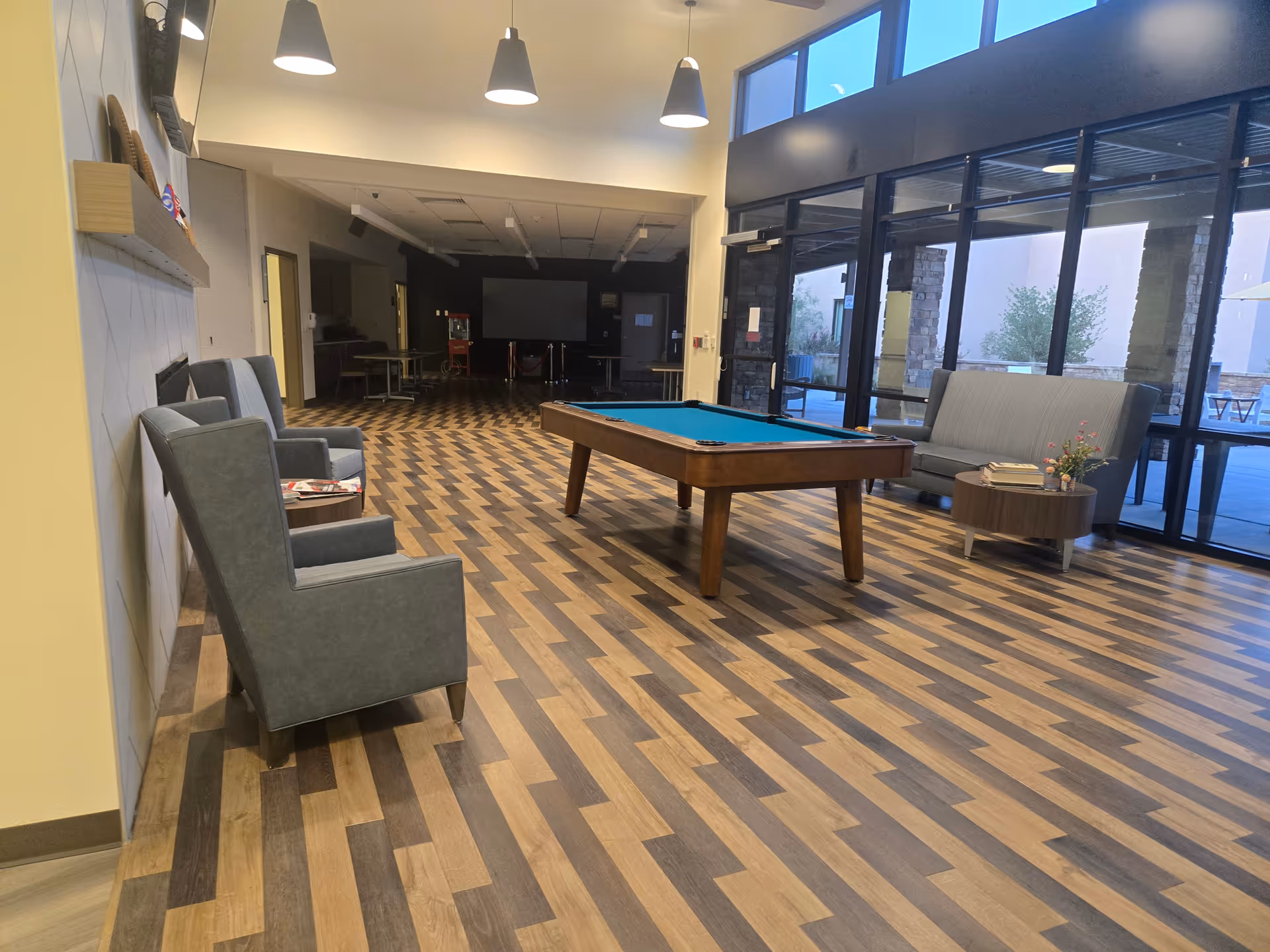 Spacious modern senior living lounge featuring a pool table, seating areas, and large windows.