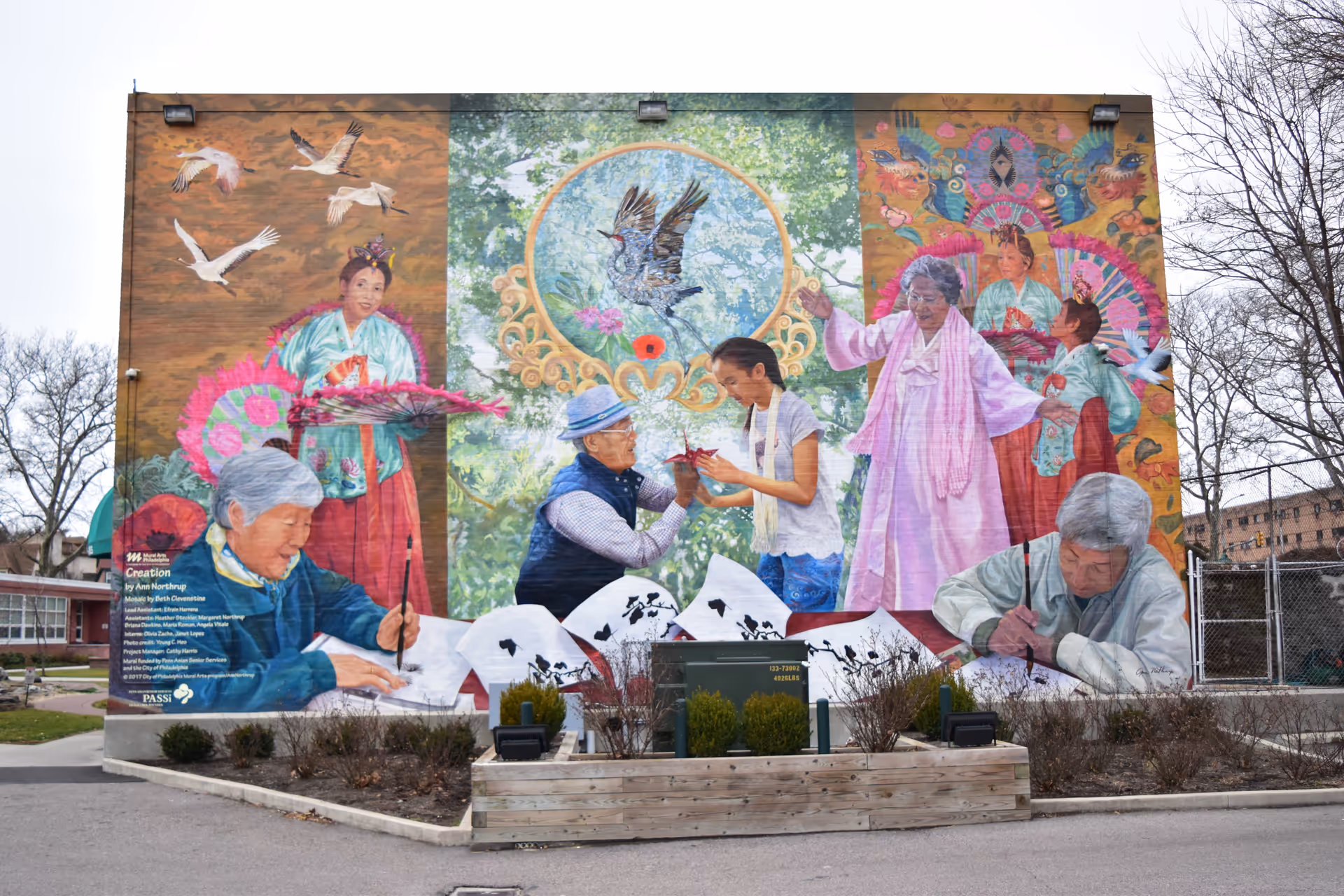 Vibrant mural on an exterior building wall shows elderly people painting and drawing.
