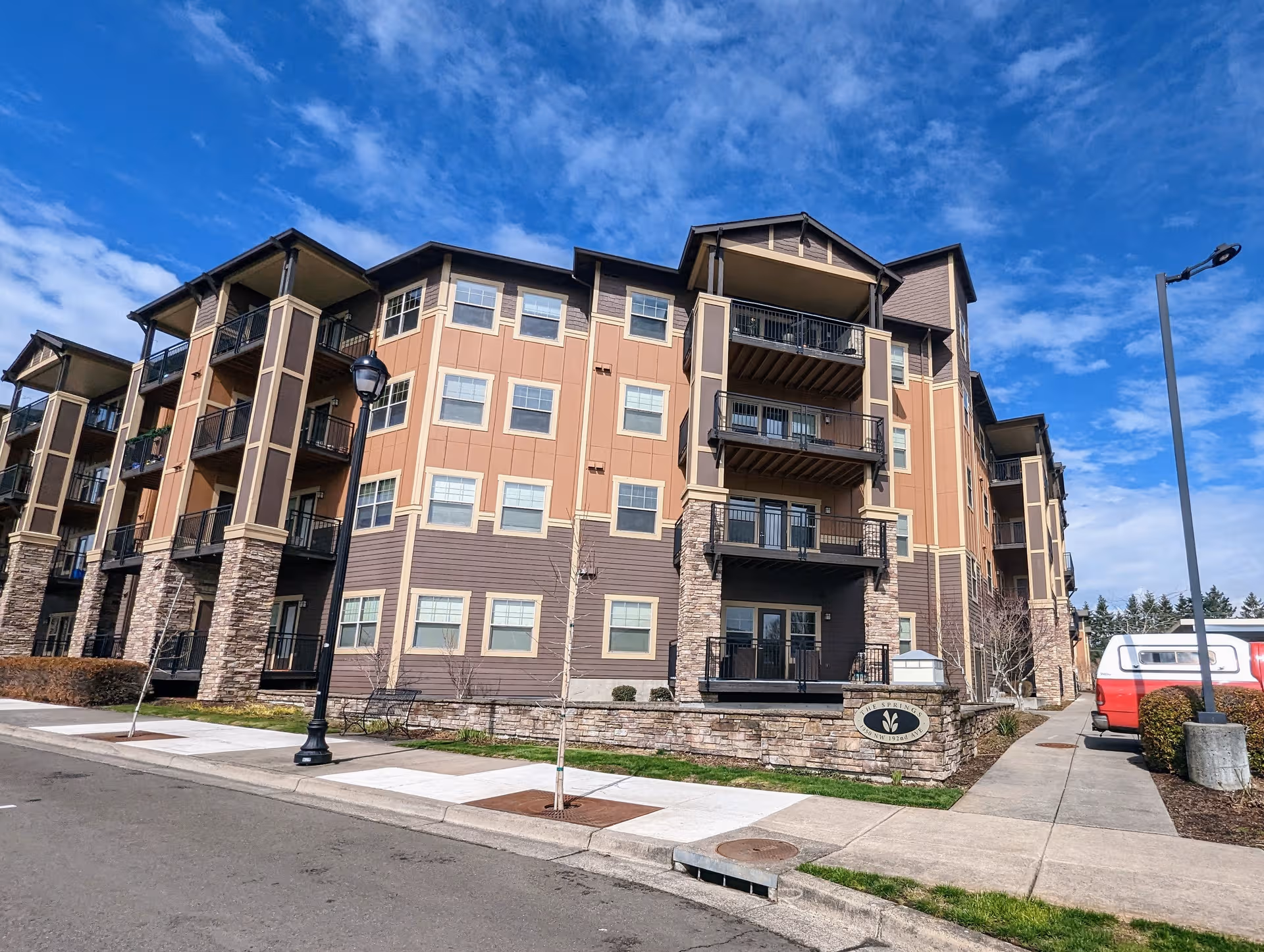 Multi-story senior living building with balconies along a clean sidewalk.