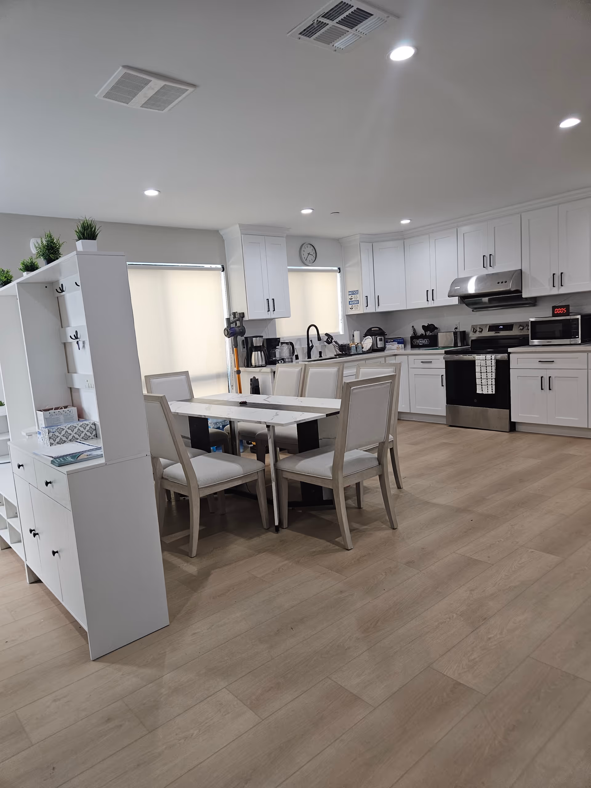 Bright white kitchen with cabinets and appliances adjacent to a dining table.