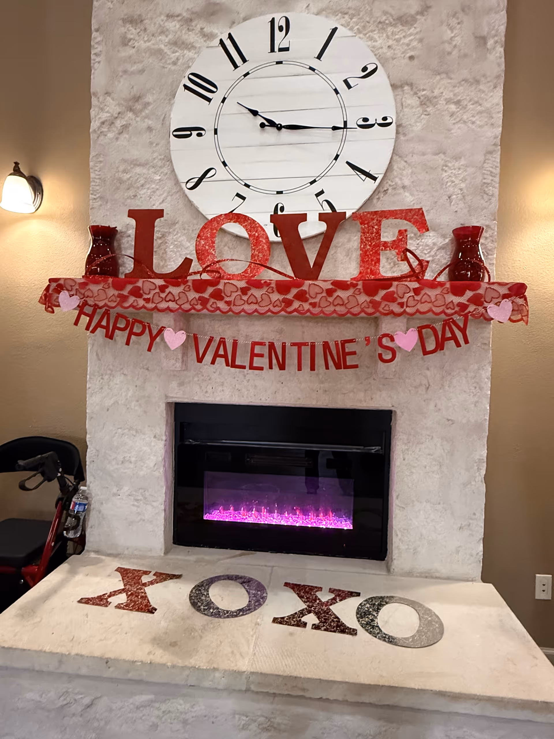 Valentine decor on a fireplace mantle beneath a large round clock.
