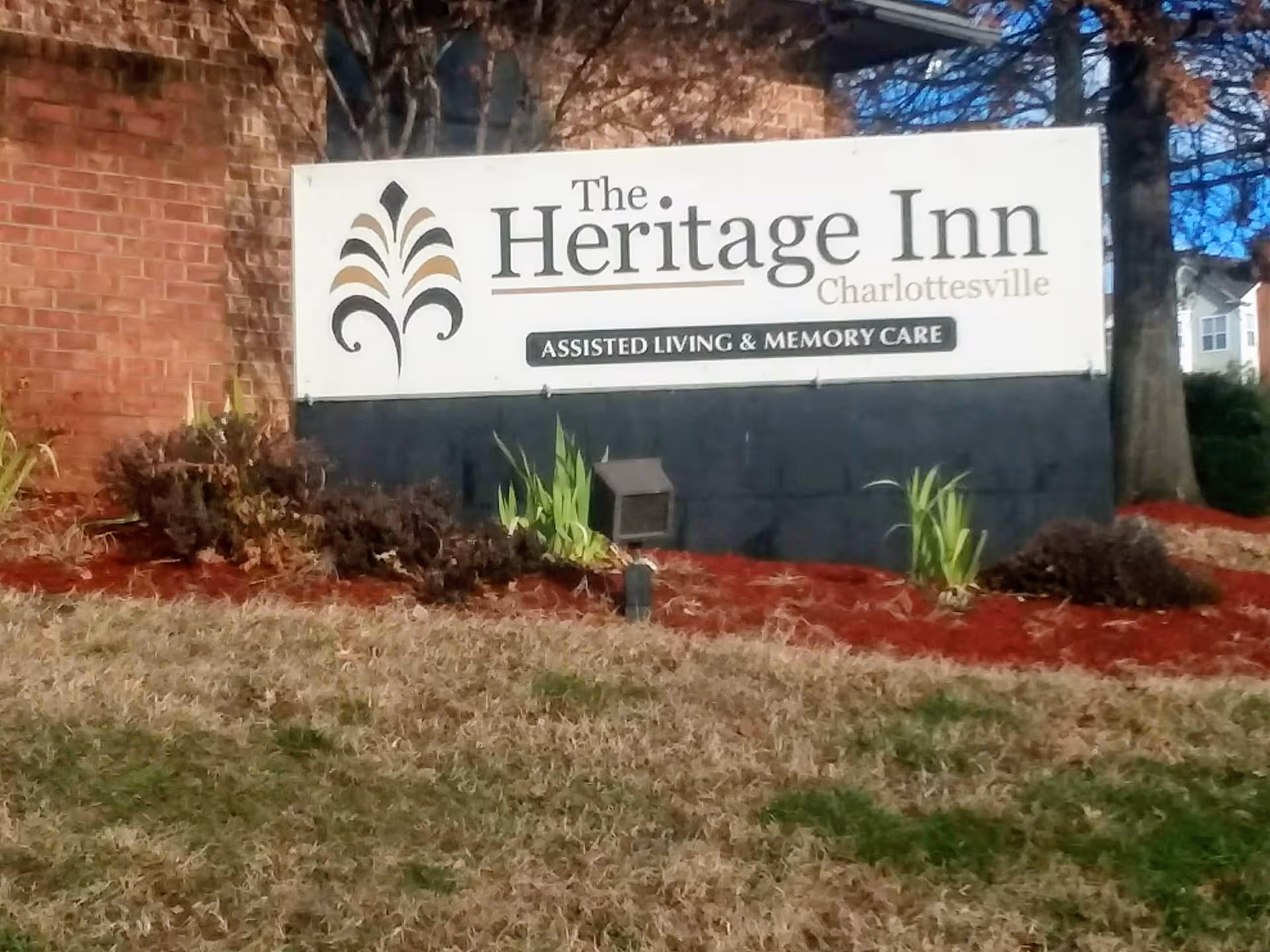 Large sign reading The Heritage Inn Assisted Living & Memory Care on a landscaped front lawn.