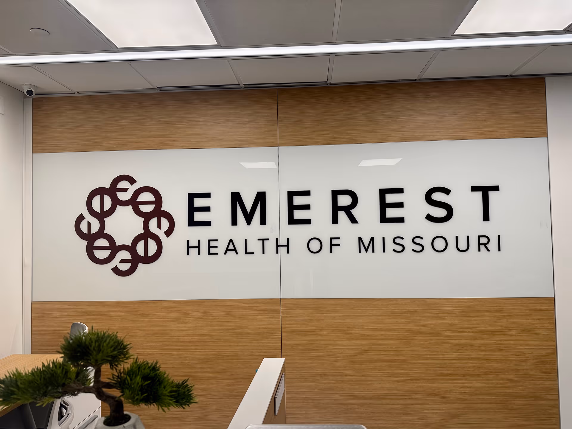 Interior reception wall with Emerest Health of Missouri logo and wood paneling.
