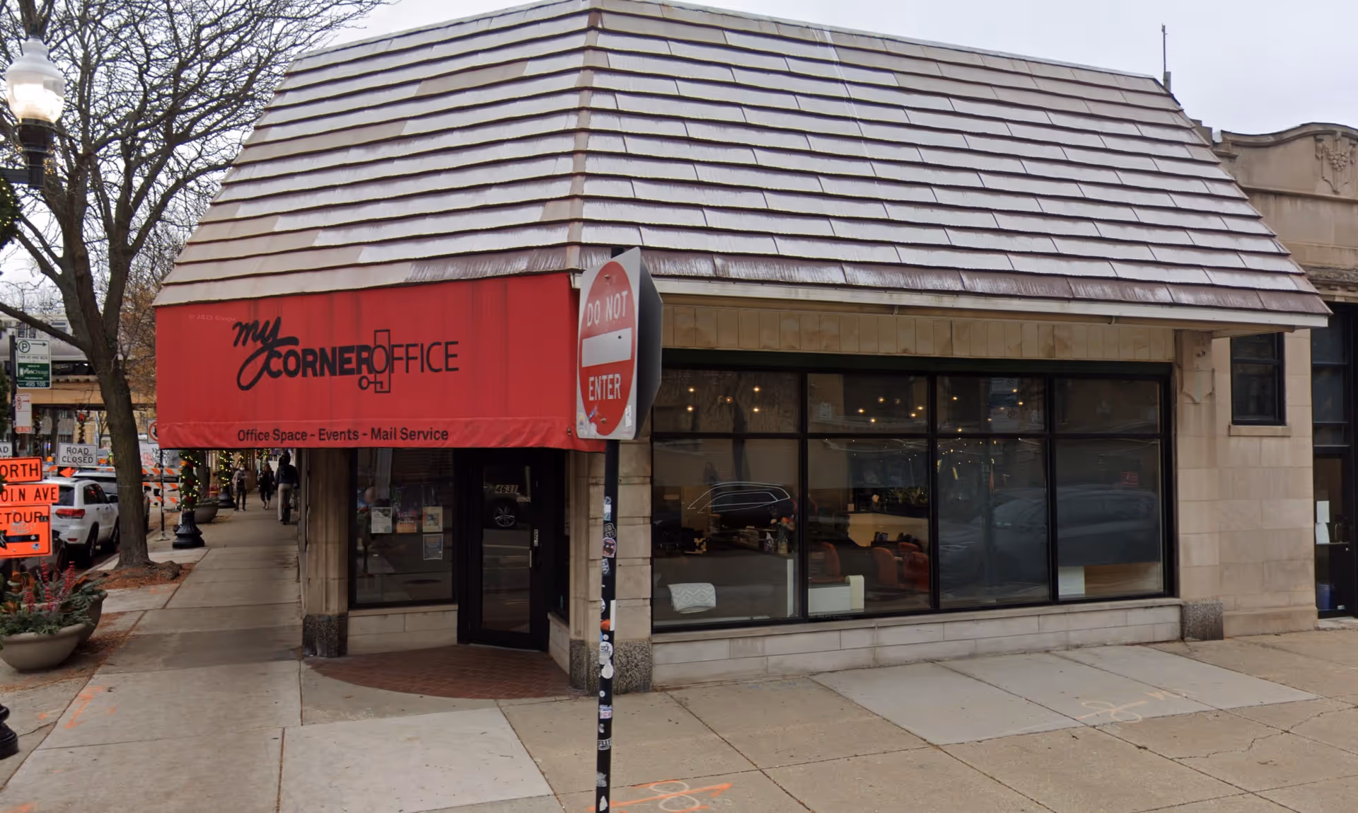 Street-level storefront with large windows and a red awning reading My Corner Office.