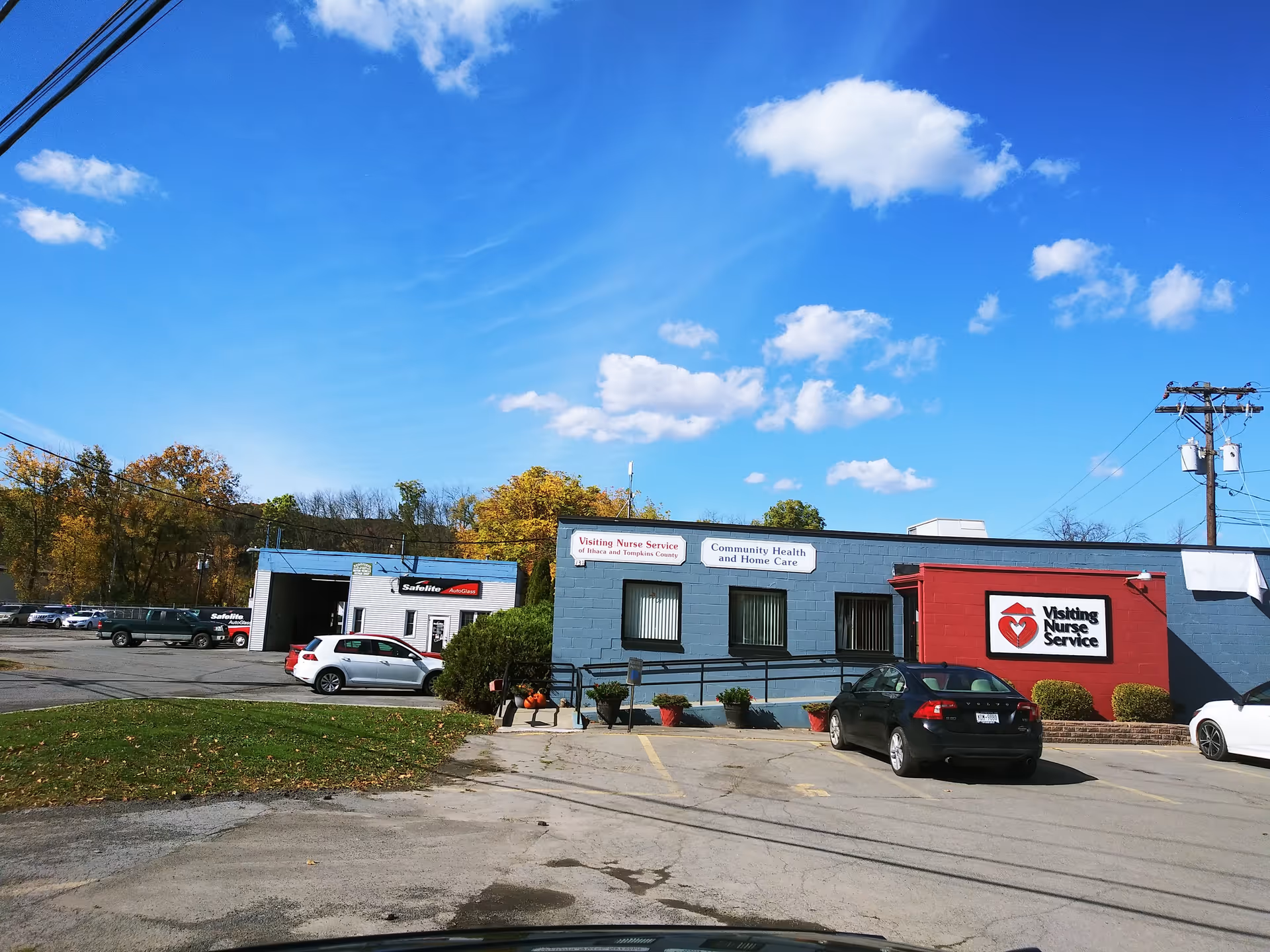 Blue single-story building with Visiting Nurse Service signage and parked cars outside.