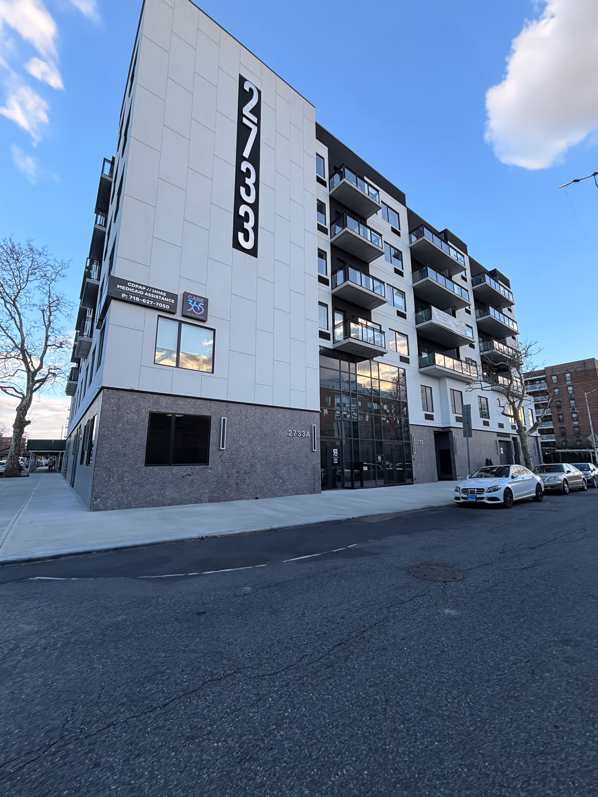 Modern multi-story building with balconies and a glass-front entrance.