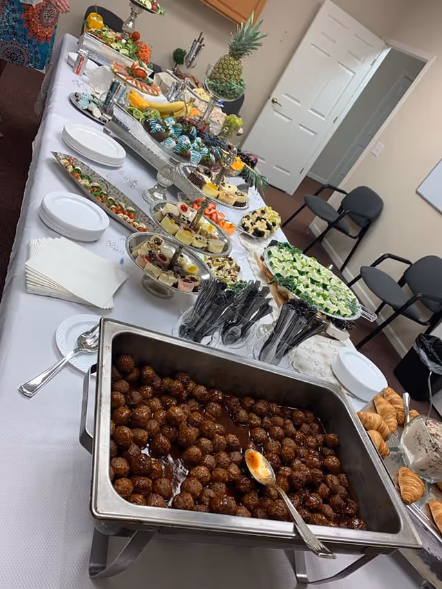 Buffet table with desserts, fruit, croissants, and beverages in a dining room.