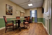 Small dining area with a round table and four chairs in a senior living facility interior.