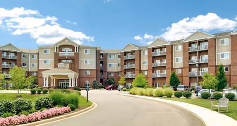 Exterior view of a multi-story senior living facility named Barrington of Oakley with a driveway, landscaped gardens, trees, and parked cars under a partly cloudy sky.