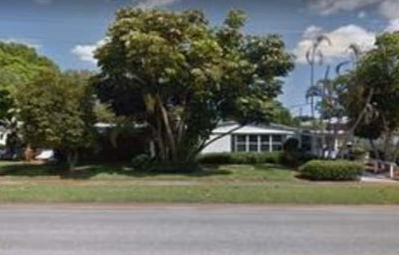 Exterior view of a single-story care center with trees along a road.