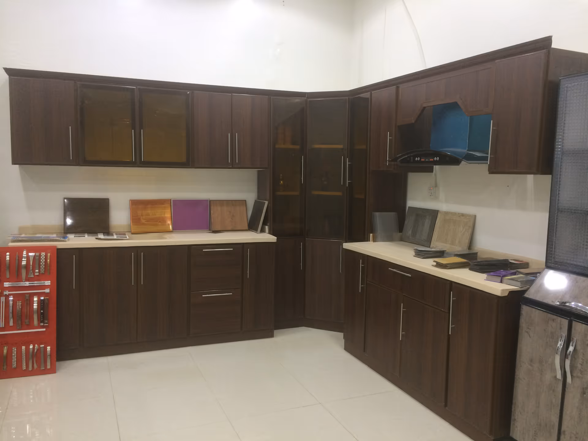 Dark wood kitchen cabinets line the walls with countertops and sample boards on display.