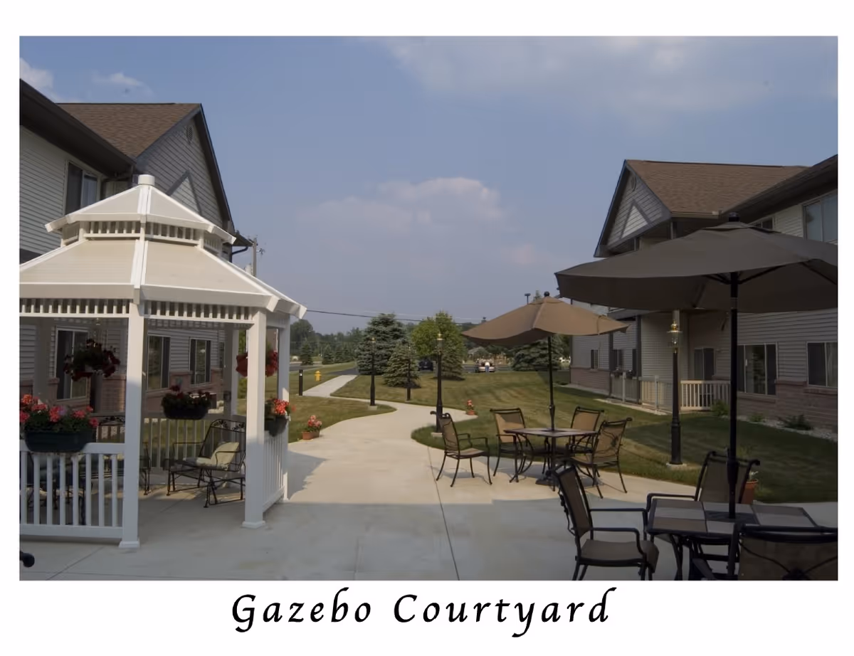 Outdoor courtyard with gazebos, patio tables, and umbrellas between residential buildings.