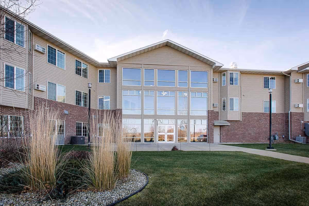 Exterior view of Prairie Meadows Senior Living building with large windows and landscaped lawn.