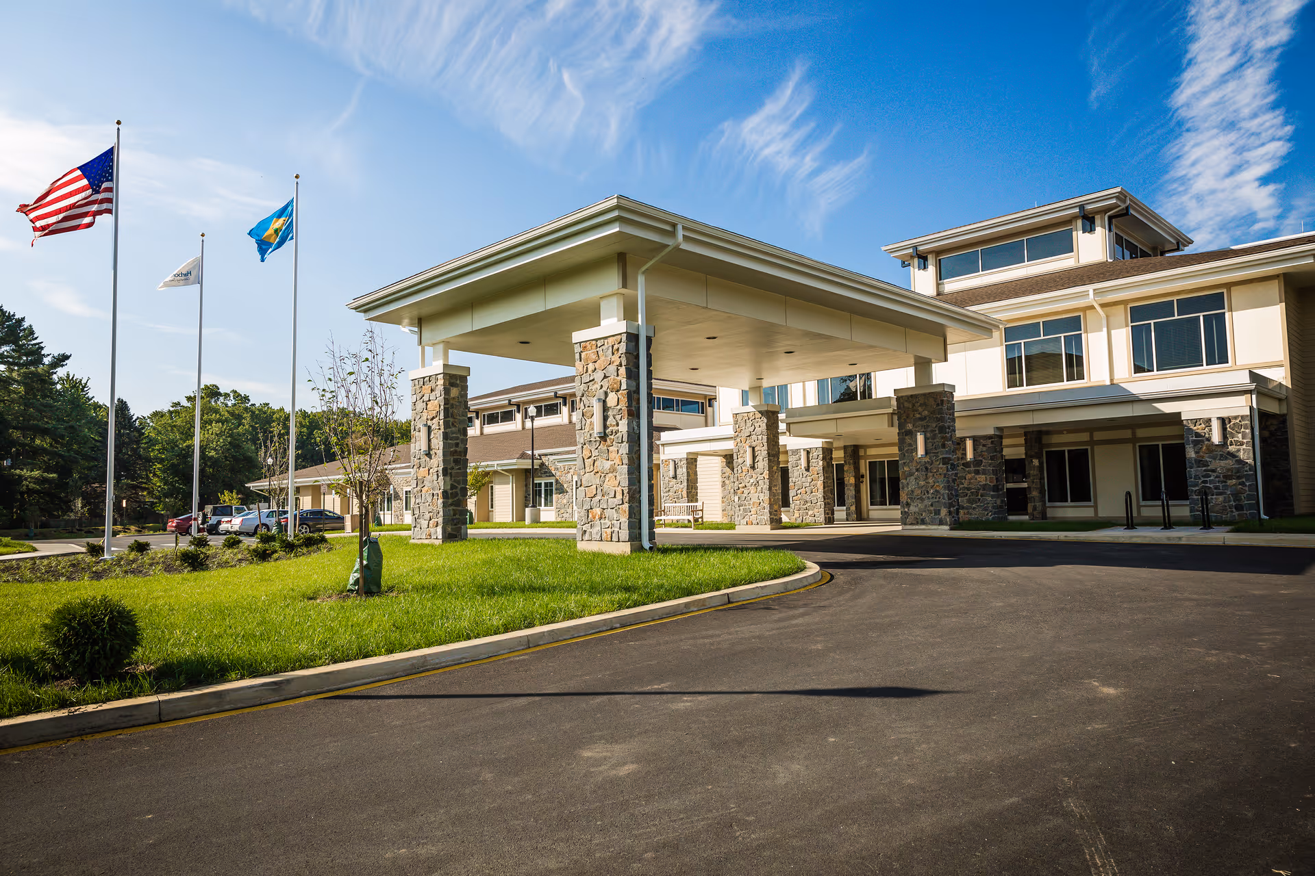 Exterior view of HarborChase of Wilmington with entrance canopy and flags.