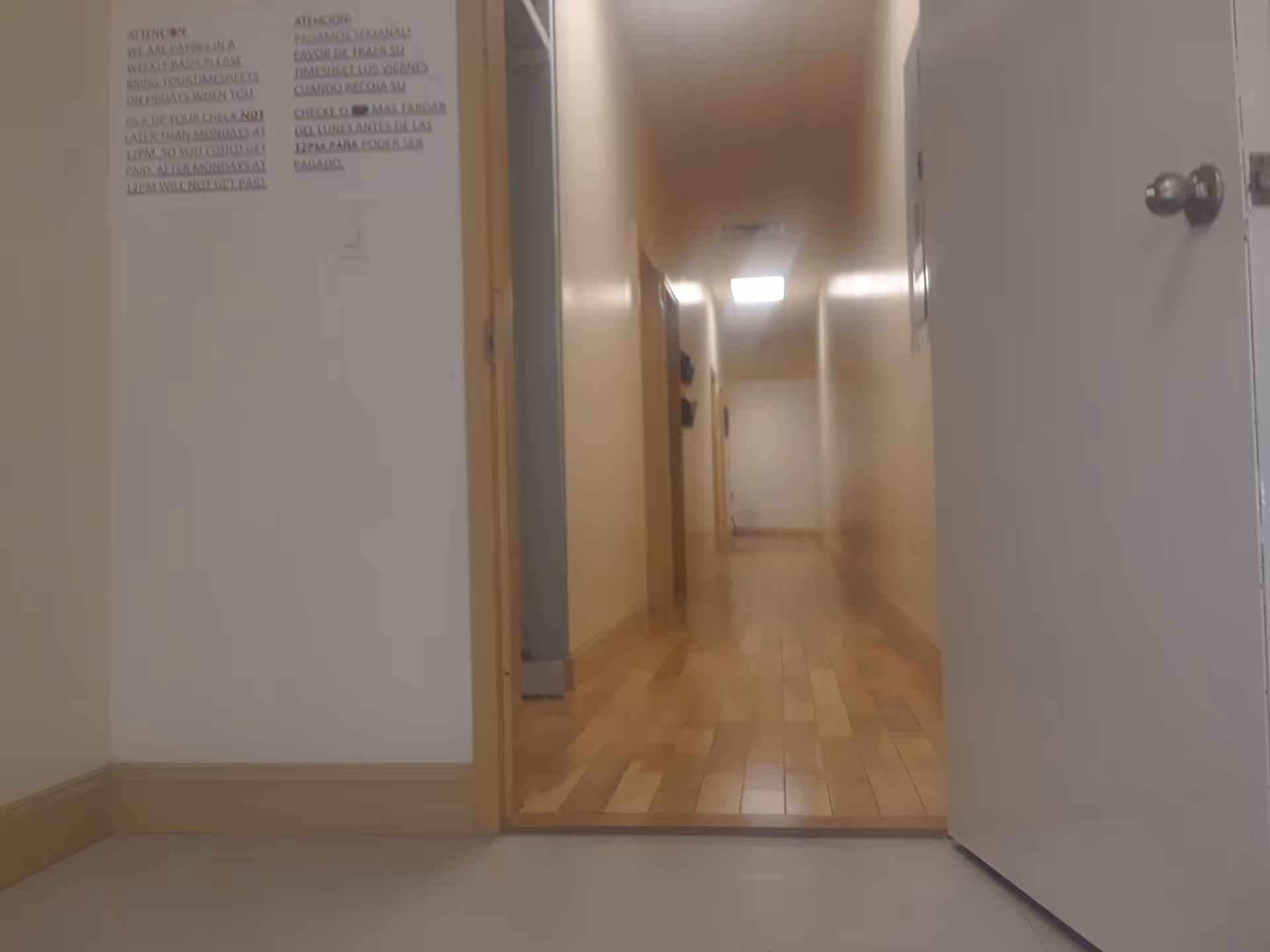 Interior hallway in a senior living facility with doors along a wooden floor.