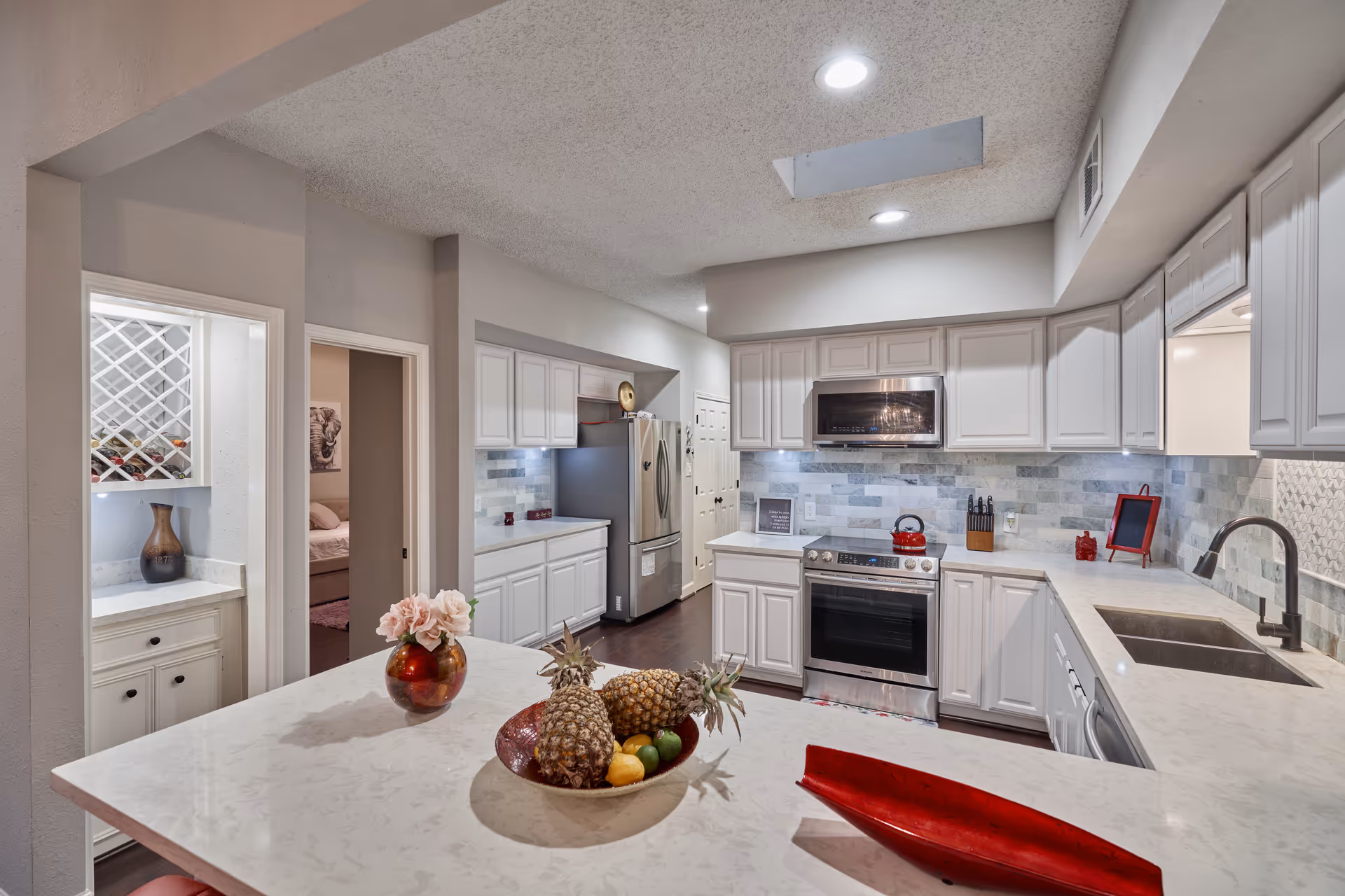 Nesta's Wellness Retreat kitchen with island, white cabinets, stainless appliances, and tiled backsplash.