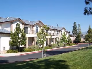 Exterior view of Inland Christian Home campus with beige buildings, trees, and a grassy lawn.