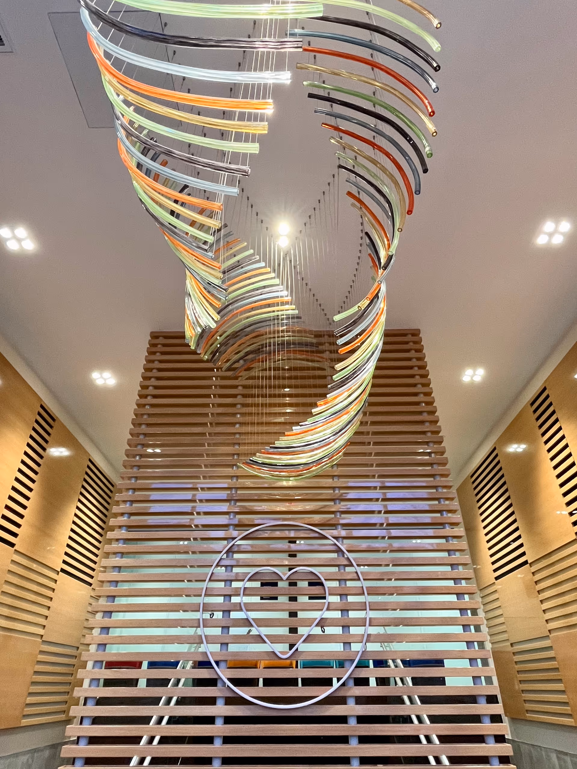 Interior lobby of a senior living facility with a colorful spiral ceiling sculpture.
