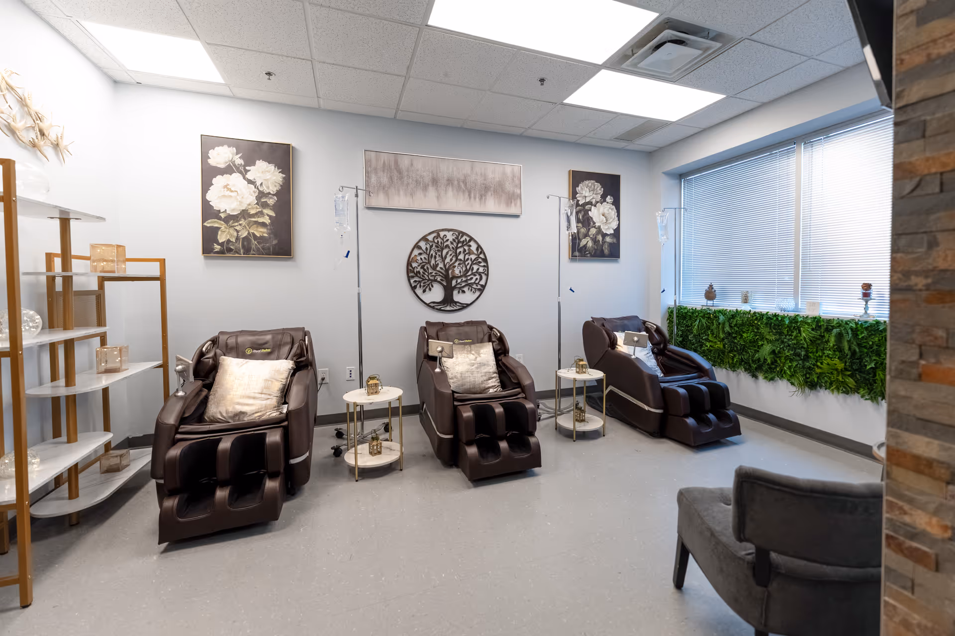 Interior spa room with three brown reclining chairs, small tables, IV stands, and wall art.