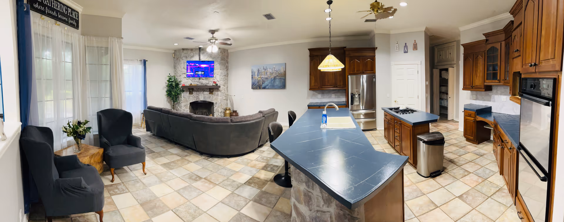 Open living area with sofa seating, fireplace, TV, and a kitchen island.