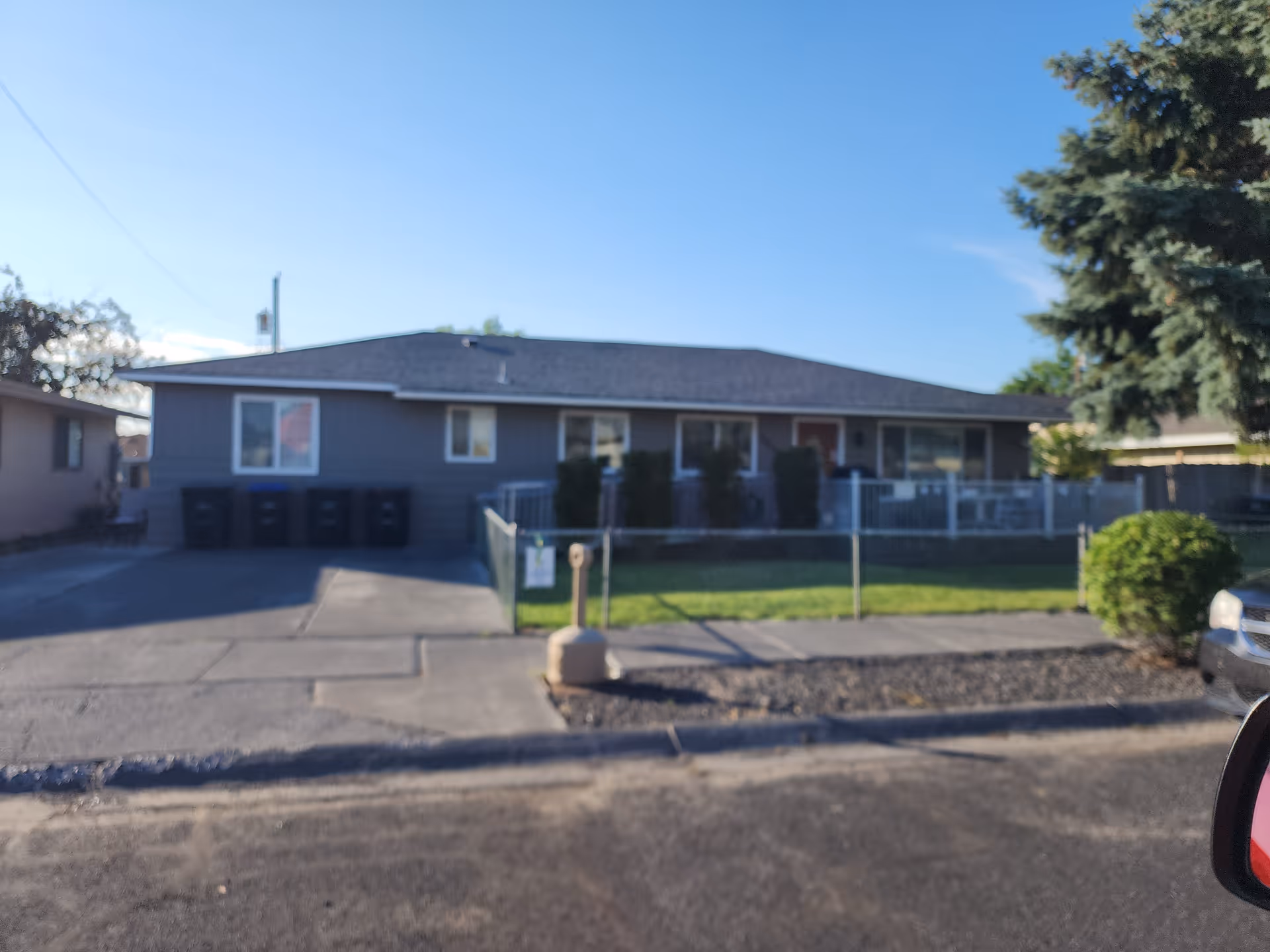 A single-story gray facility with a fenced front yard on a residential street.