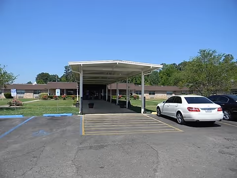 Covered drop-off driveway at a senior facility with a white car parked.