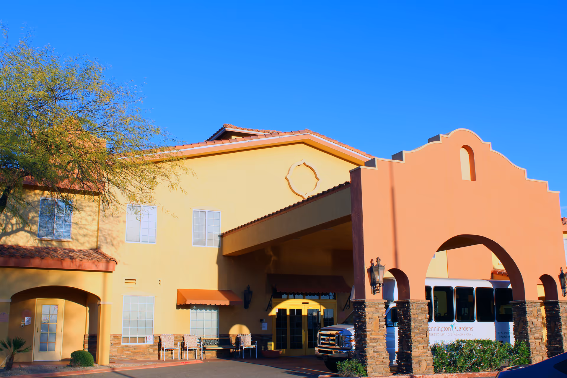 Colorful senior living facility facade with arched entrance and bus
