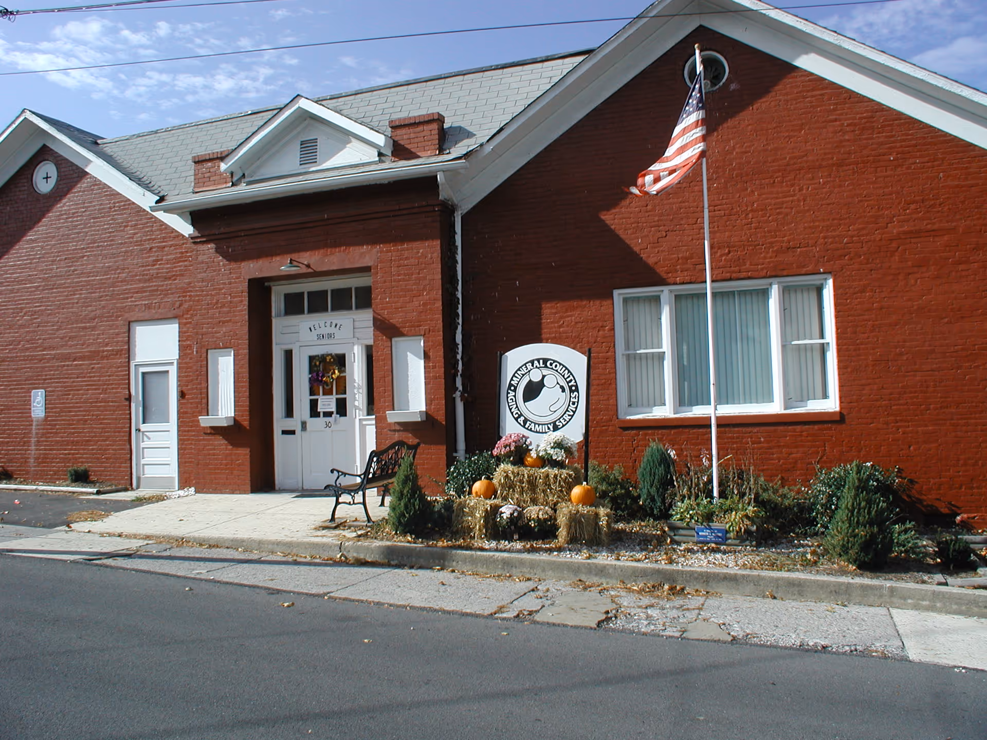 Exterior view of the Aging & Family Services building with American flag and fall decorations.