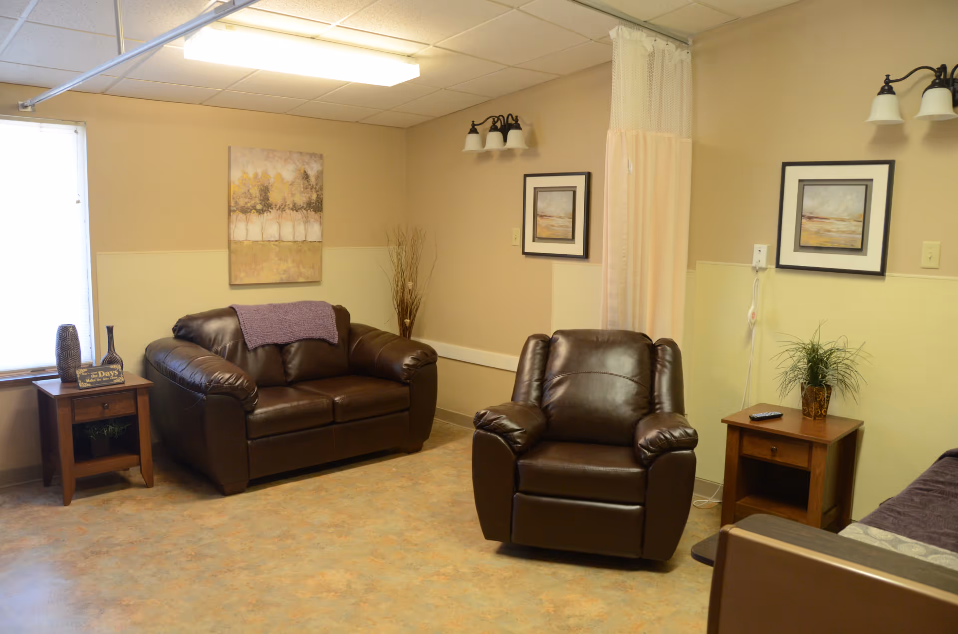 Cozy senior living lounge with leather seating, side tables, and wall art.