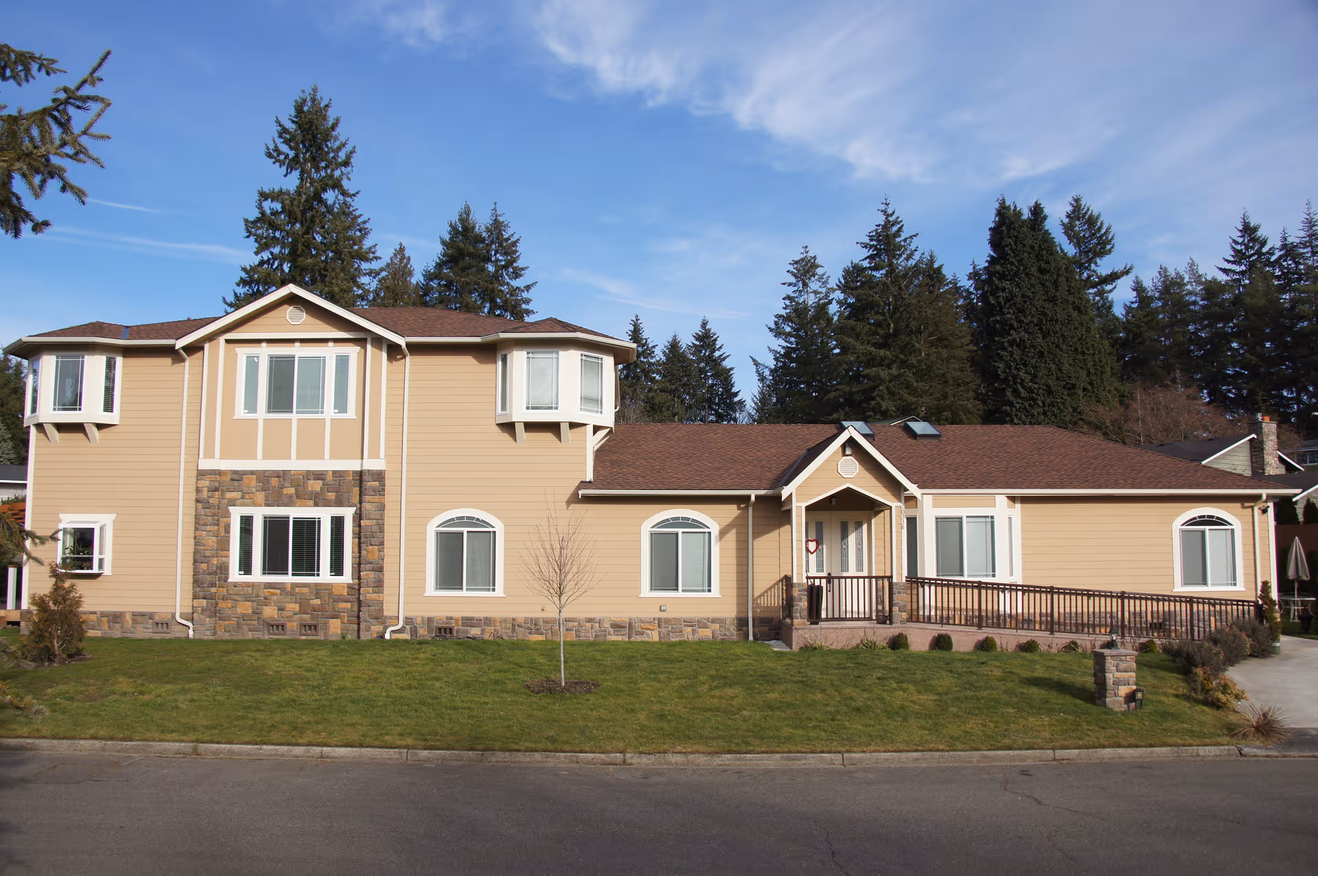 Exterior view of Sun Village Senior Care building with beige siding and stone accents.