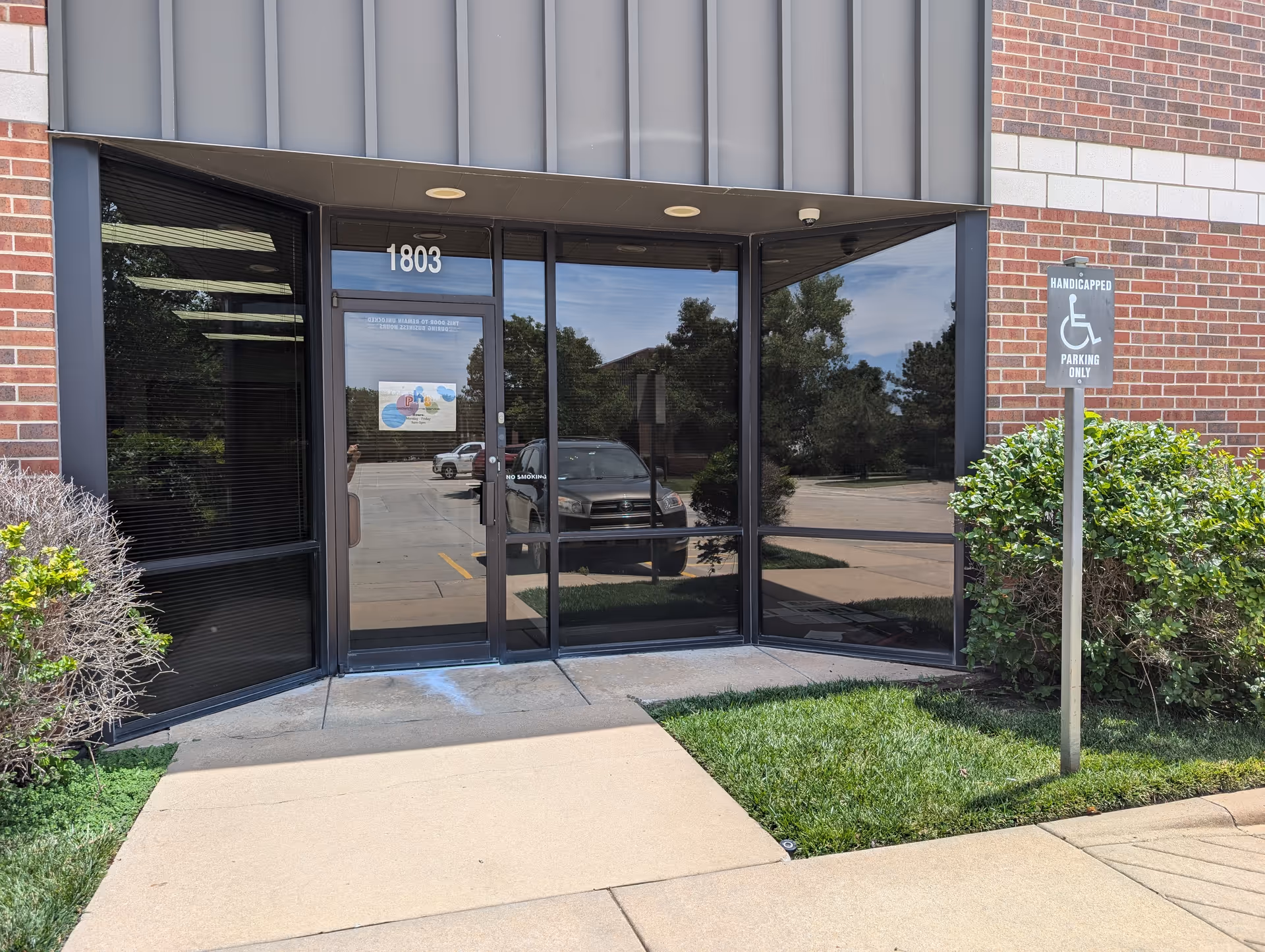 Entrance to Pediatric Home Service facility with glass doors and handicap parking sign.