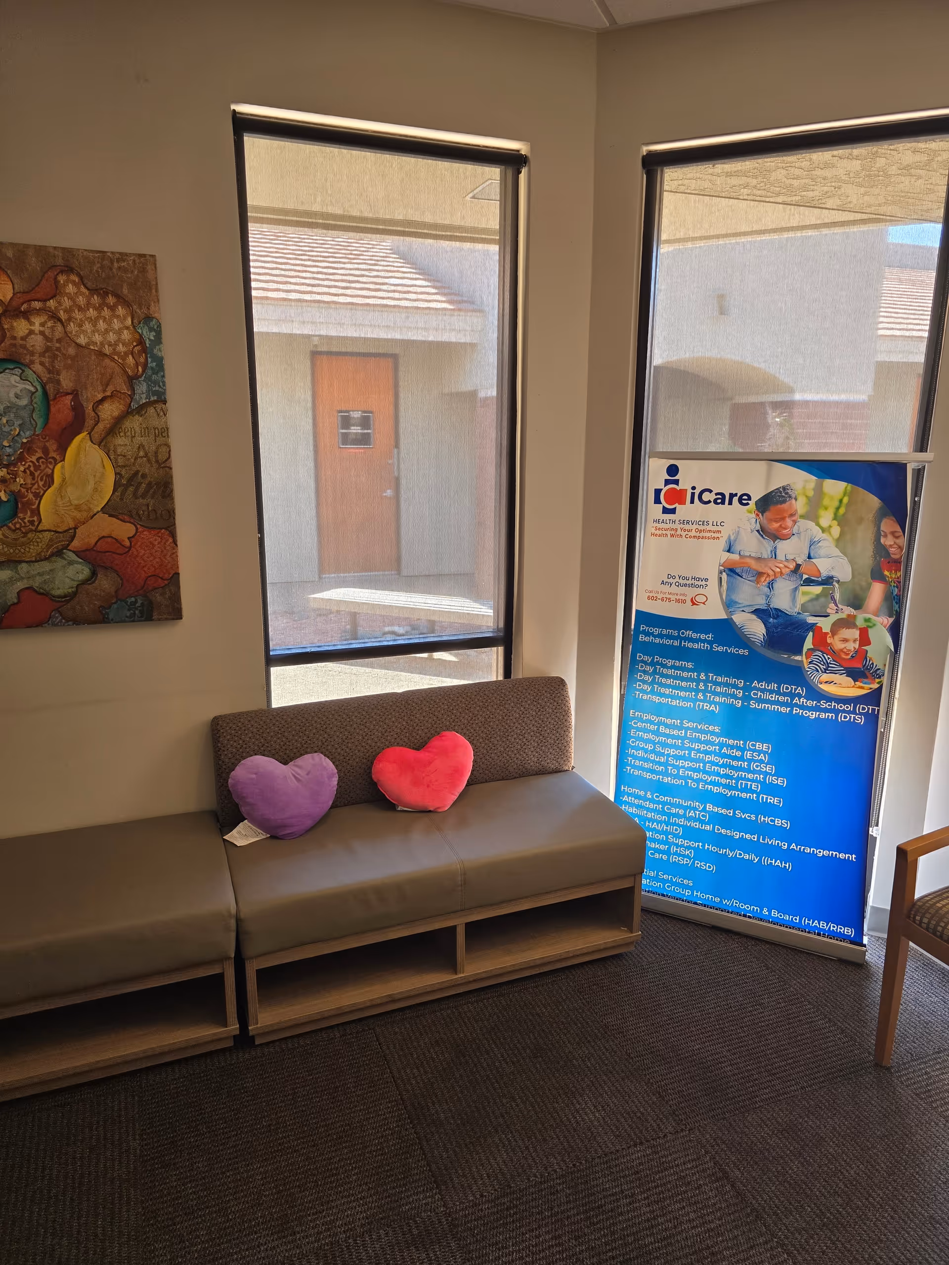 A lounge area with a beige sofa, heart-shaped cushions, windows, and a promotional banner.