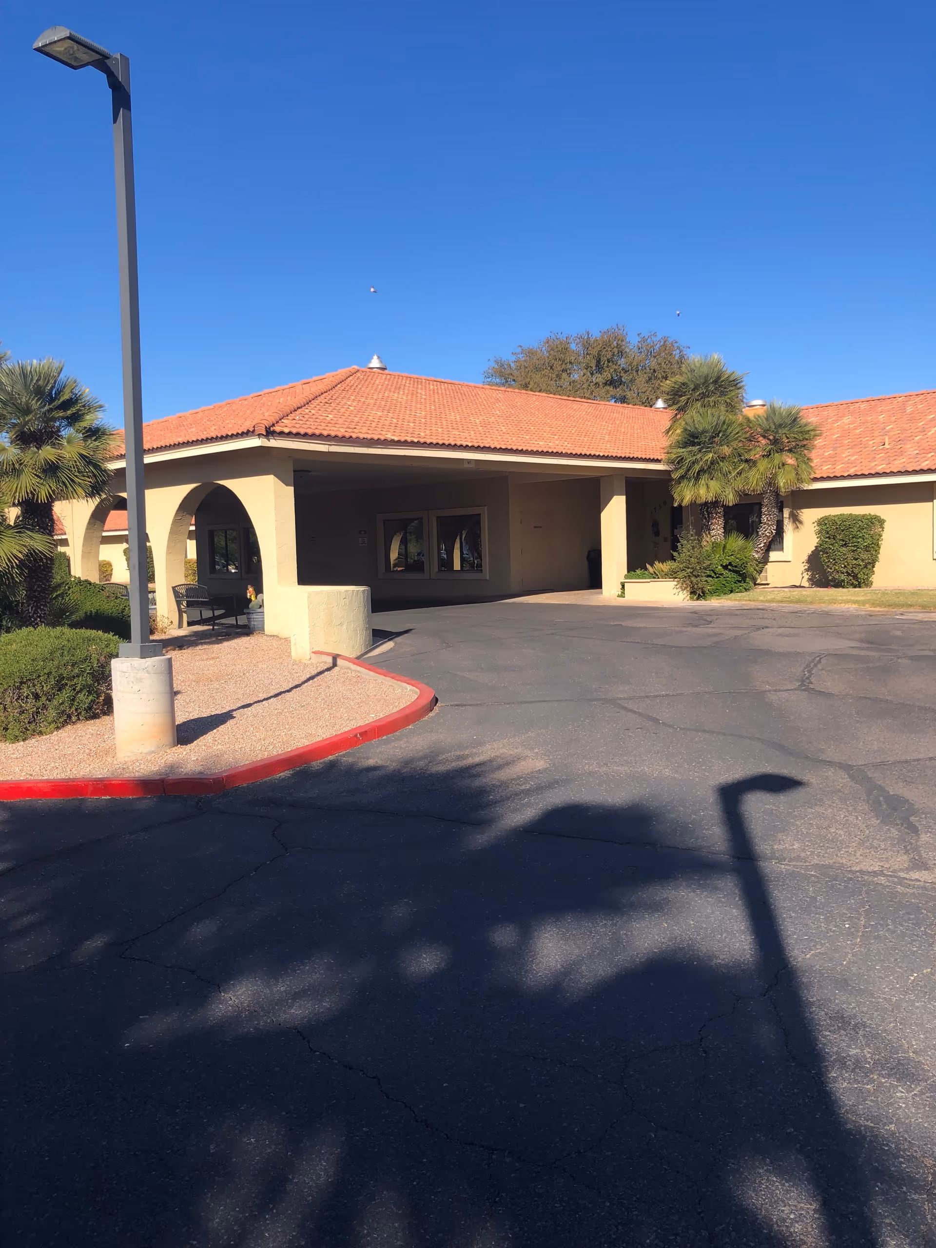 Desert Cove Nursing Center exterior with covered entrance, driveway, and palm landscaping.