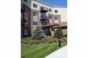 Exterior view of a multi-story senior living building with balconies and landscaped grounds.