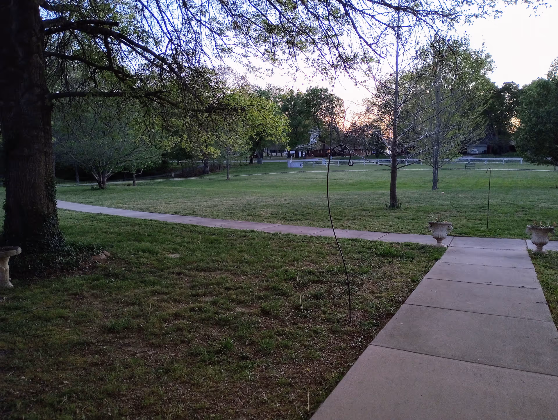 Expansive grassy park area with a concrete walkway and trees.
