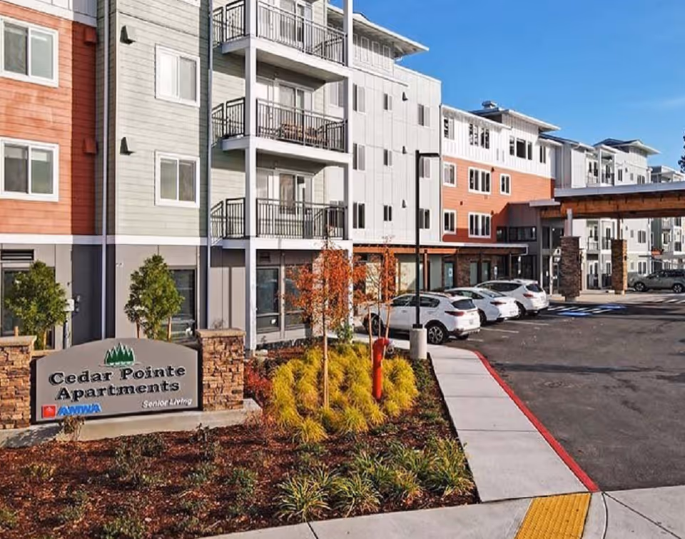 Exterior view of Cedar Pointe Apartments with parked cars and landscaped entrance.