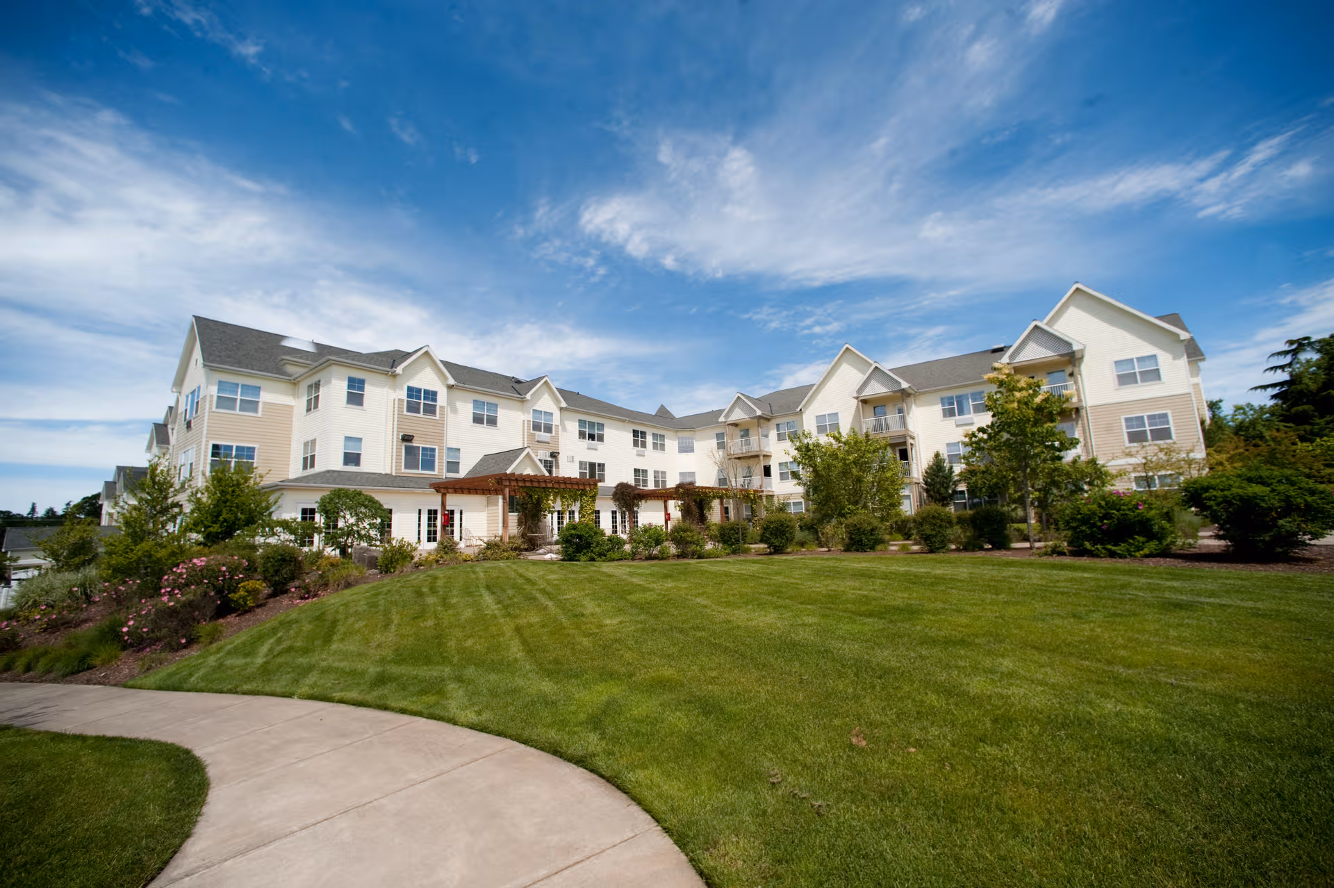 Exterior view of Avamere at Bethany senior living building with green lawn and sidewalk.
