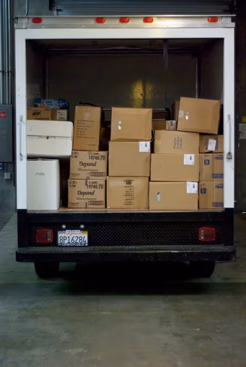 Back of a loading truck interior with stacked cardboard boxes and supplies