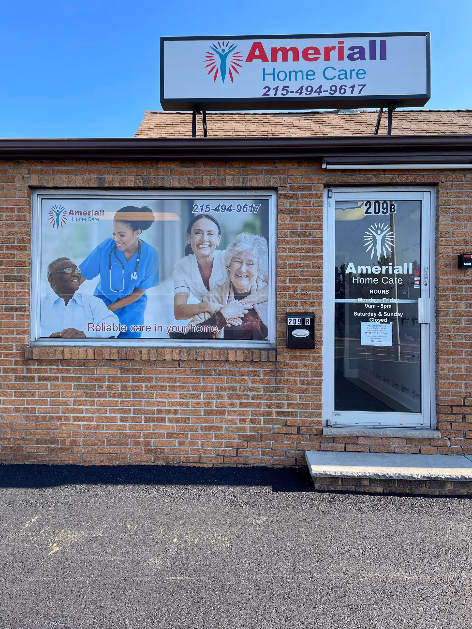 Brick storefront with Ameriall Home Care sign and a large window advertisement near entrance.