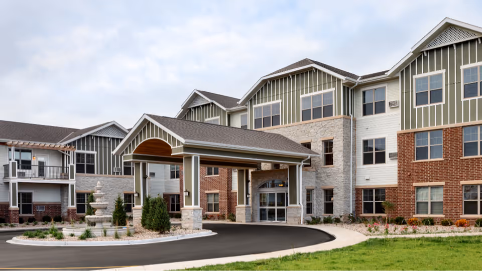 Exterior view of Aspire Senior Living Oshkosh showing a multi-story entrance and curved driveway.
