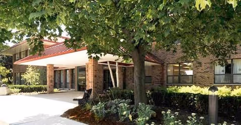 Exterior view of Alden Estates of Naperville: brick building, covered entrance, and landscaping.