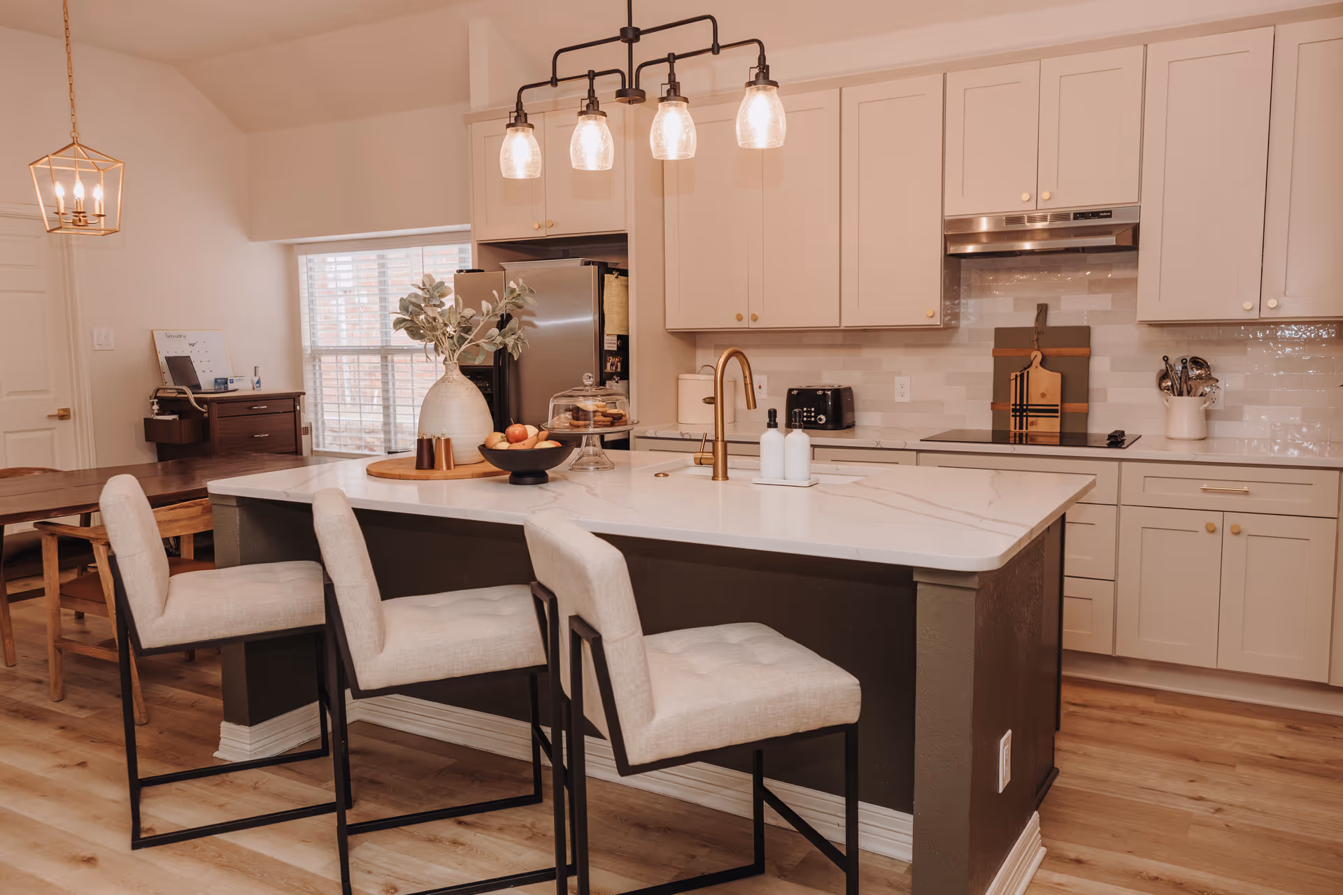 Modern kitchen in a senior living facility with an island, stools, and white cabinets.