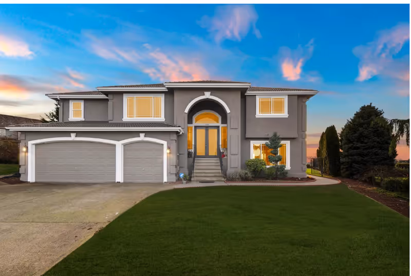 Front view of a gray two-story house with three garage bays and manicured lawn.