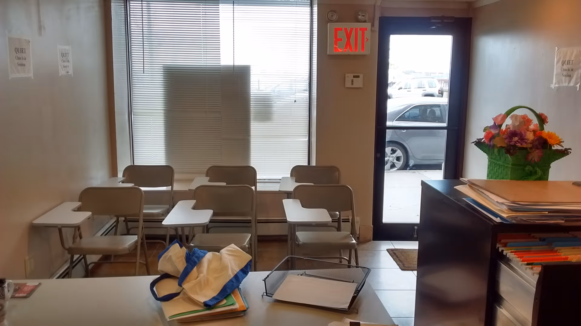 Small waiting room with stacked chairs, a desk, and a floral basket near the door.