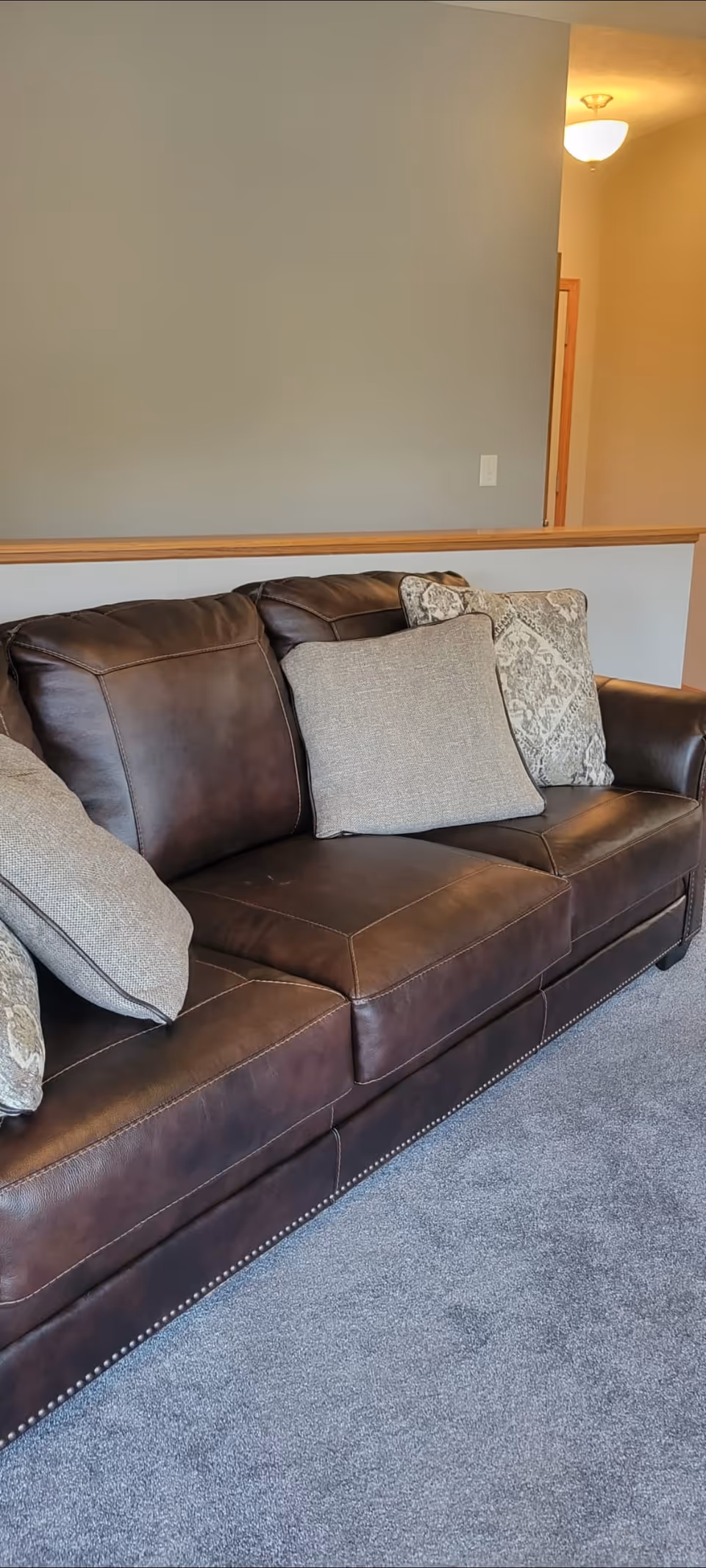 Brown leather sofa with beige pillows in a cozy living room.