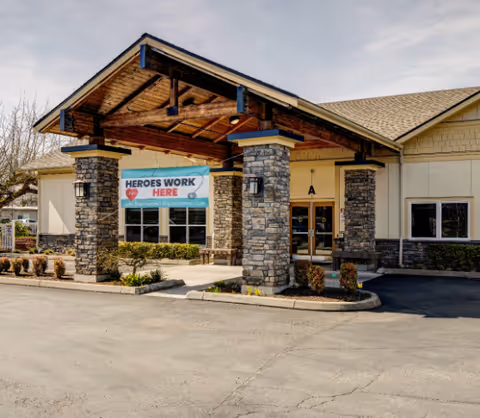 Entrance of an assisted living facility with stone pillars and a banner reading Heroes Work Here.